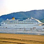 Visto da praia, Costa Concordia navega no Canal do Estuário enquanto deixa o Porto de Santos