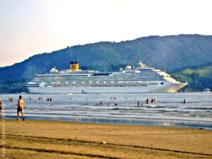 Visto da praia, Costa Concordia navega no Canal do Estuário enquanto deixa o Porto de Santos