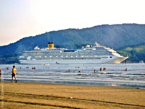 Visto da praia, Costa Concordia navega no Canal do Estuário enquanto deixa o Porto de Santos