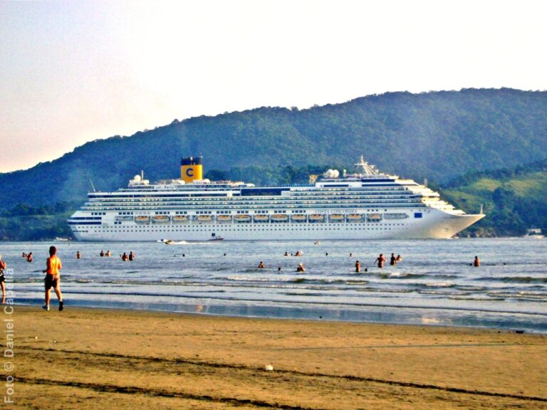 Visto da praia, Costa Concordia navega no Canal do Estuário enquanto deixa o Porto de Santos