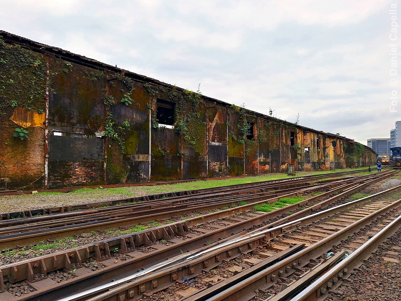 Antigo armazém portuário de tijolos com fachada envelhecida e trilhos de trem em primeiro plano, característico da região do Valongo no Porto de Santos