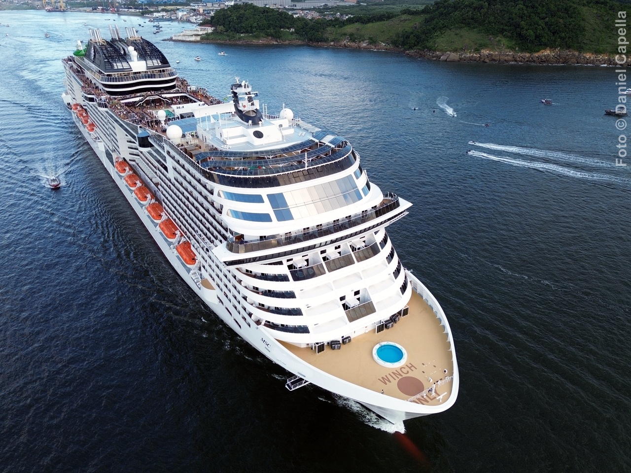 Vista aérea imponente da proa e dos decks superiores do mega navio MSC Virtuosa navegando por águas costeiras