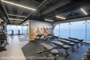 Nova academia do navio equipada com área de pesos, bancos e vista panorâmica para o mar