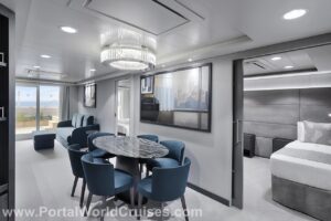 Ampla sala de estar e jantar da Royal Suite do MSC Yacht Club, com mesa de mármore, cadeiras azuis, quarto integrado e portas de vidro com acesso a um terraço externo privativo, novidade da reforma do MSC Musica