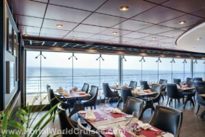 Salão interno do restaurante Butcher's Cut com mesas postas, cadeiras de couro escuro e amplas janelas panorâmicas com vista para o rastro do navio no mar, parte da reforma do MSC Musica