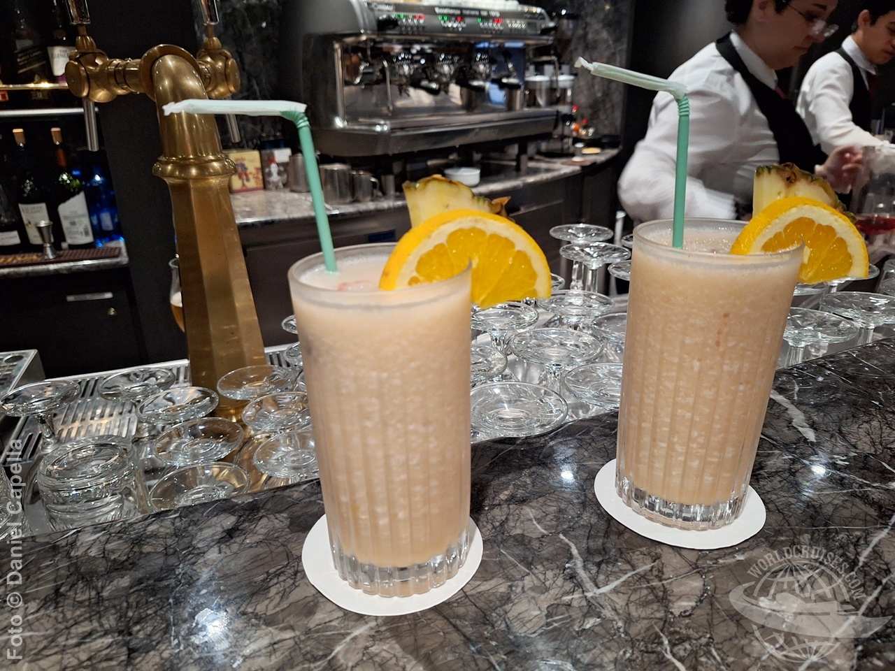 Imagem mostra dois coqueteis no bar do MSC Yacht Club a bordo do MSC Preziosa, com bartender ao fundo