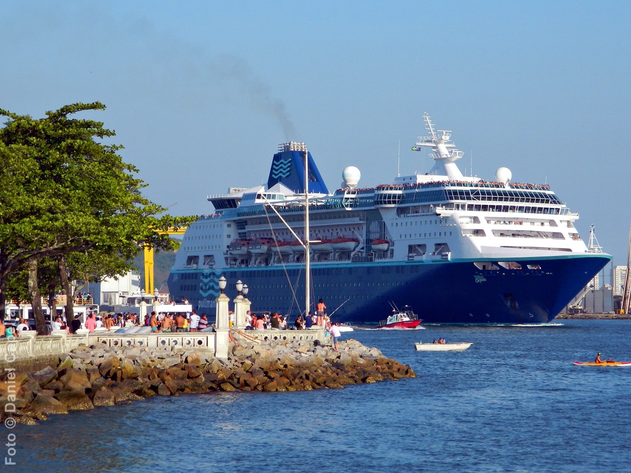 Navio Empress da Pullmantur navegando no canal portuário de Santos enquanto é observado pelo público na Ponta da Praia, representando o histórico de operações de cruzeiros fretados pela CVC no Brasil